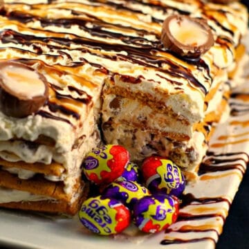 easter creme egg cake on white tray with slice removed and whole easter creme eggs in spot where slice is removed