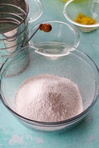 cake flour and ¼ cup sugar sifted into bowl with sifter and lemon and lemon juice in background