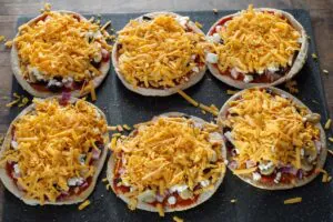 pita pizzas with cheese sprinkled on