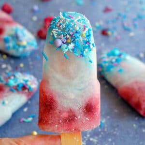 blue raspberry popsicle being held up with more in the background