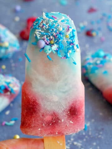 blue raspberry popsicle being held up with more in the background