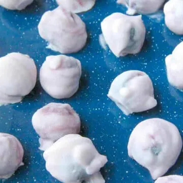 Yogurt covered blueberries on a blue surface