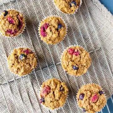 7 double berry muffins on a wire rack with beige linens underneath