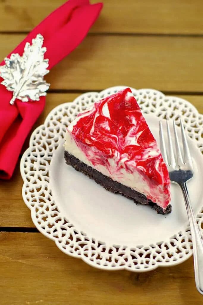 a piece of strawberry rhubarb cheesecake on a white plate with a red napkin with Canadian flag napkin ring