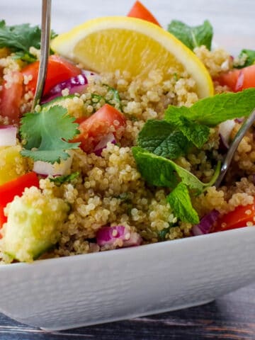 quinoa salad with spoon sticking out, in white bowl
