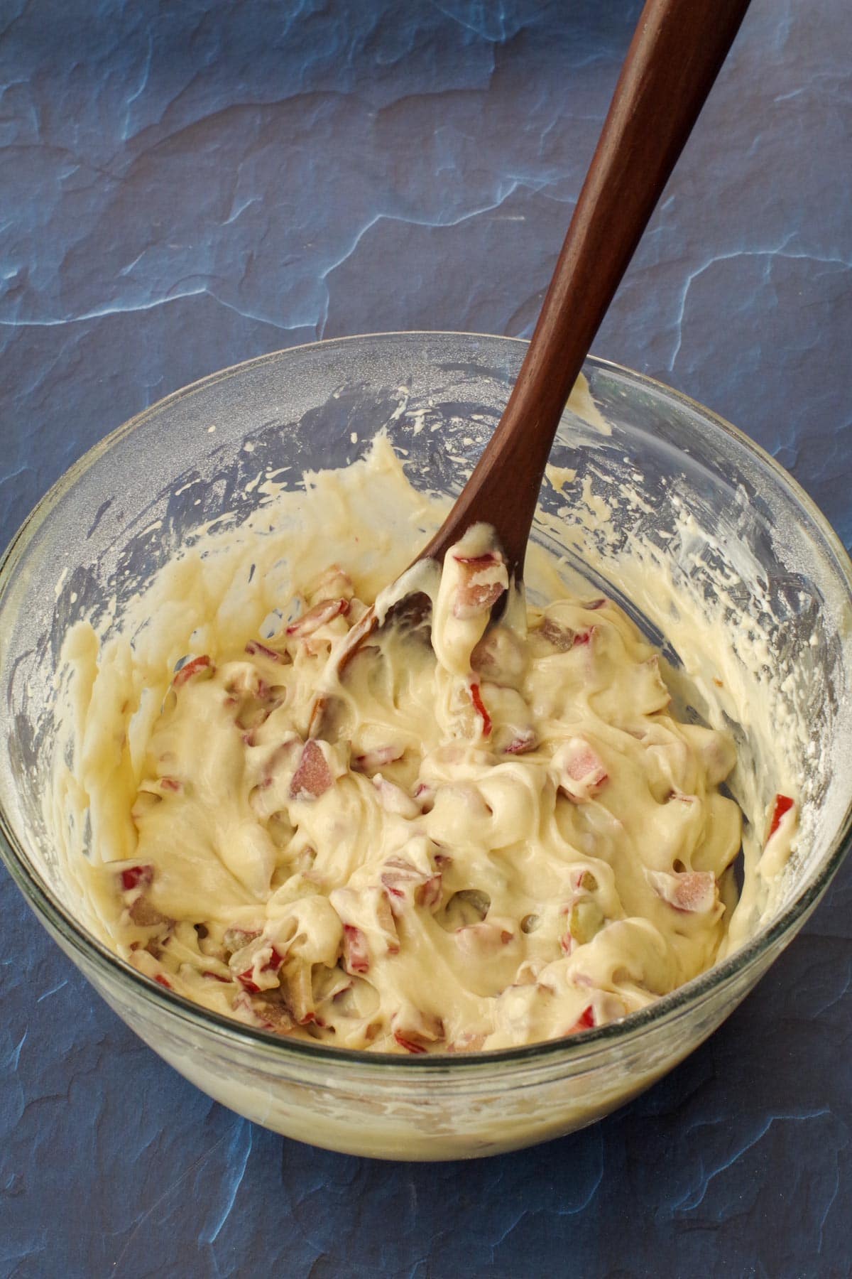rhubarb folded into cake batter, with dark wooden spoon