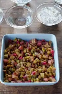 rhubarb in the bottom of a blue pan with other bowls of ingredients in background