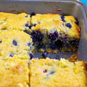 Blueberry Cornbread in a pan with a piece missing