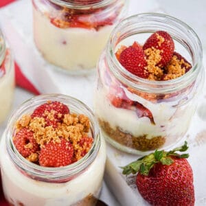 raspberry cheesecake shots in jars on a white surface