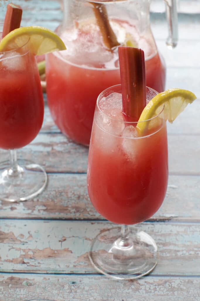 rhubarb lemonade in a glass with a pitcher and another glass in the background