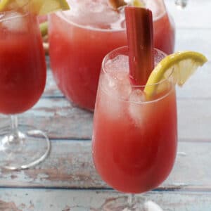 rhubarb lemonade in a glass with a pitcher and another glass in the background