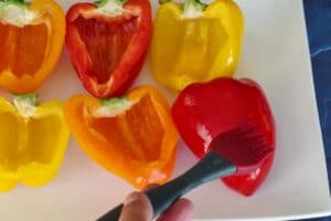 oil being brushed on peppers on white platter