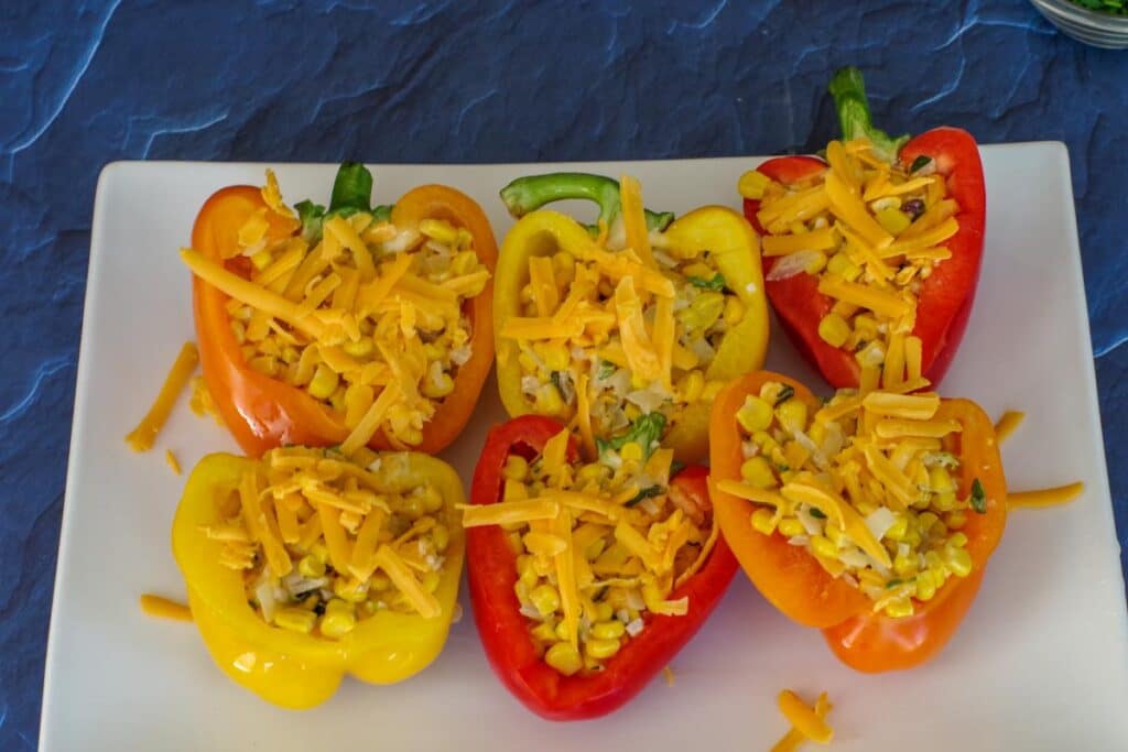 6 pepper halves stuffed with corn mixture on a white platter