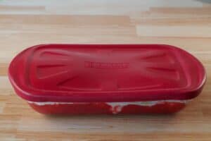 glass 9X13 pan with red plastic lid on counter