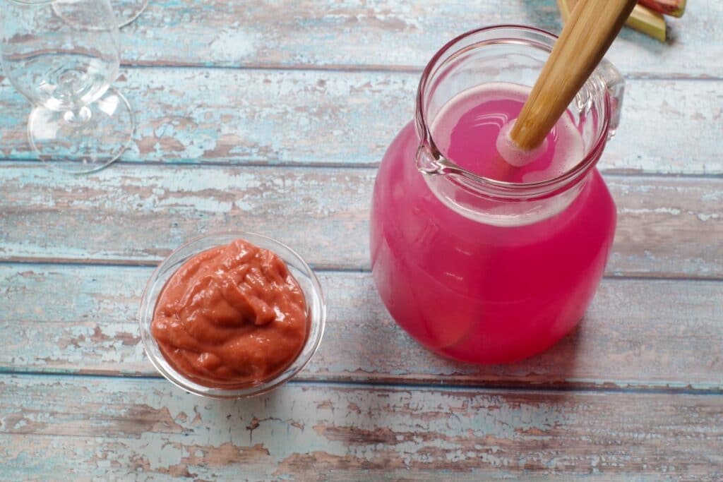 rhubarb compote in a glass dish and glass jug of pink lemonade