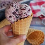 hand holding Saskatoon Berry ice cream in a waffle cone