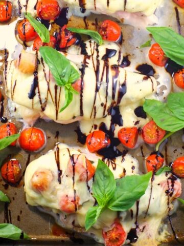 Sheet pan Caprese Chicken on sheet pan with basil and grape tomatoes