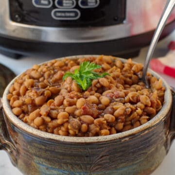 slow cooker baked beans in pottery with slow cooker in background