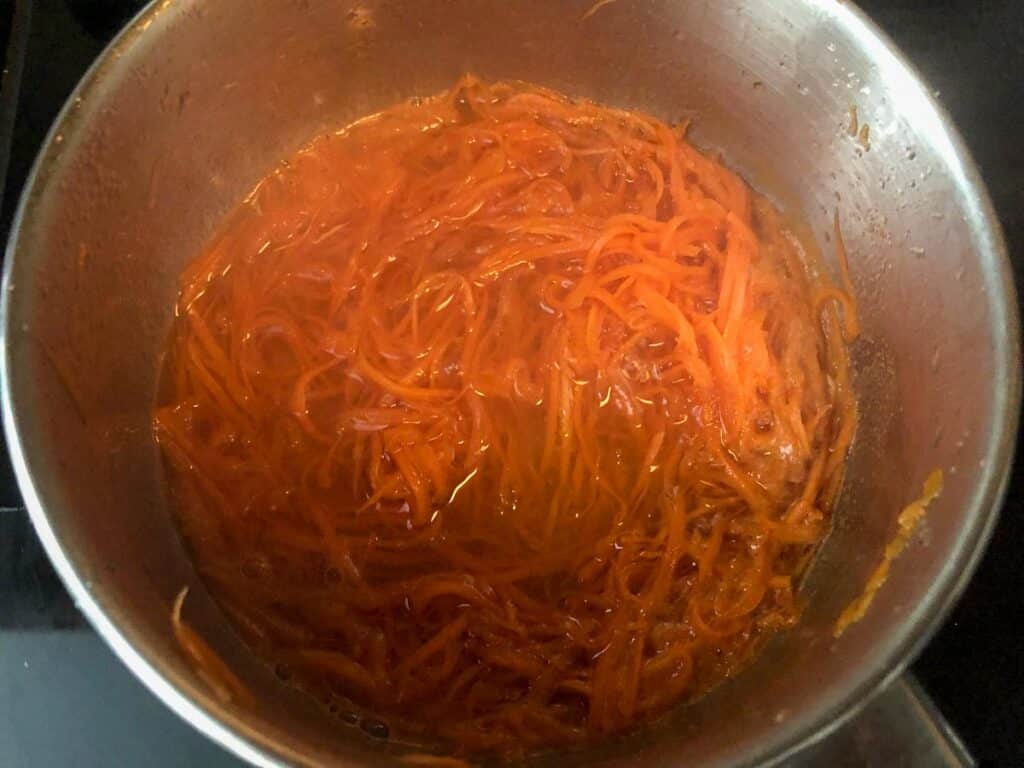 shredded carrot in saucepan with sugar and water