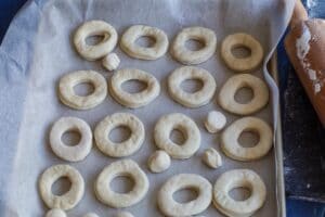 uncooked donuts on parchment covered baking sheet