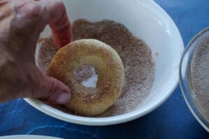 donut being rolled in cinnamon sugar