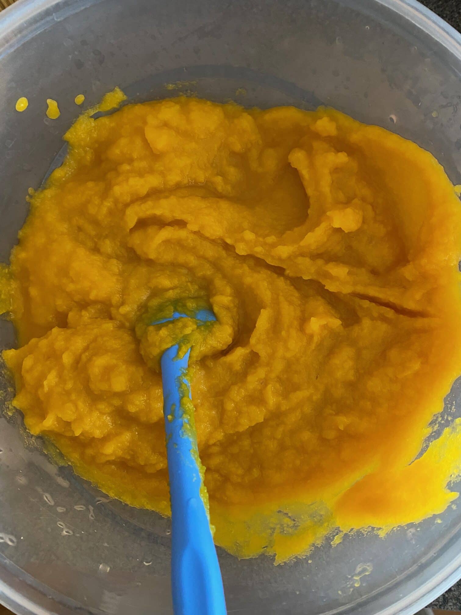 pureed pumpkin in a bowl with a blue spatula