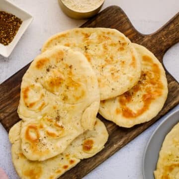 4 pieces of naan bread on a dark wood cutting board
