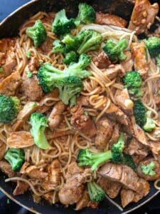 sliced pork with sauce, broccoli, and noodles in a frying pan