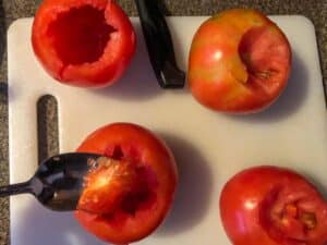 spoon scooping out inside of tomato