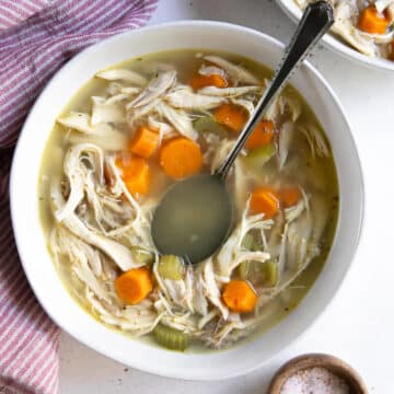 chicken noodle soup in white bowl with spoon in it