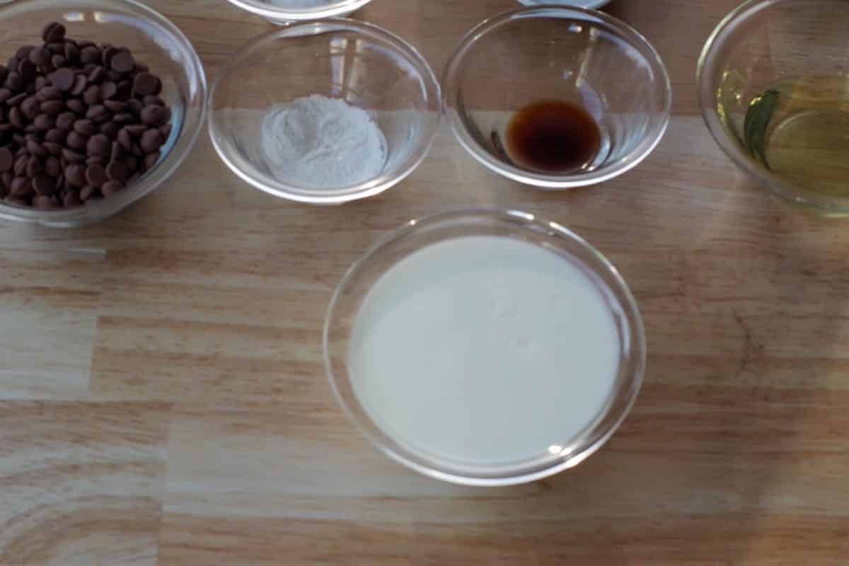 vinegar mixed with milk in a glass bowl with small glass bowls with ingredients in the background