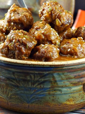 slow cooker sweet and sour meatballs in a hand made pottery serving bowl