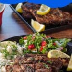 Cut Greek ribs on a plate with Greek rice and salad, with fork on plate and platter of ribs in the background