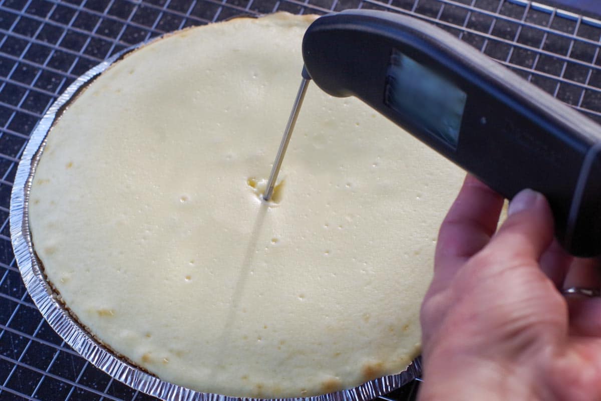 Apple cheesecake pie with thermometer in it (on wire cooling rack)