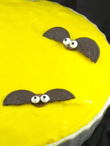 Yellow Moon halloween pie, with chocolate bats in white pie dish, on black surface