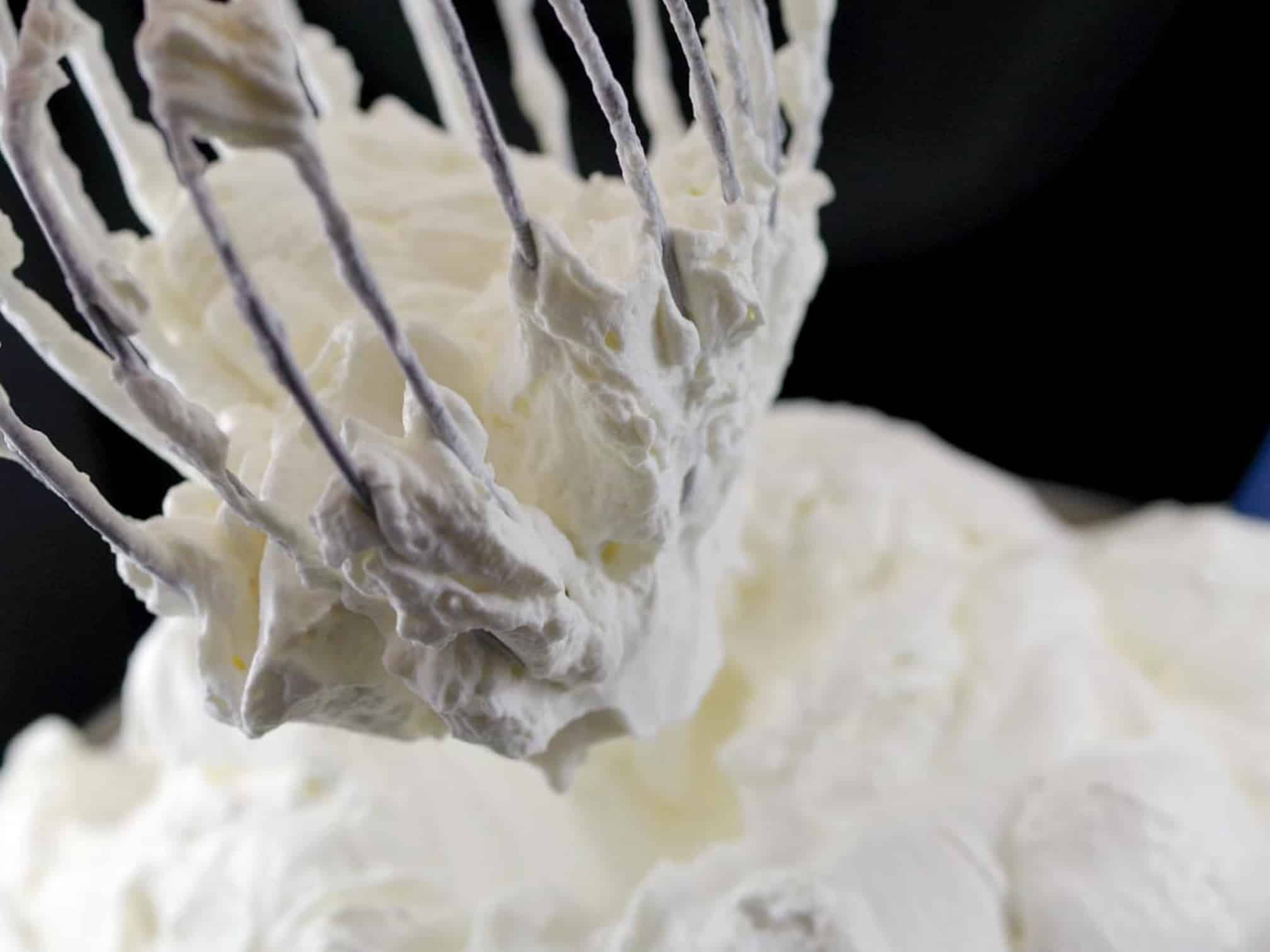 whipped cream on a stand mixer whisk over a bowl of whipped cream
