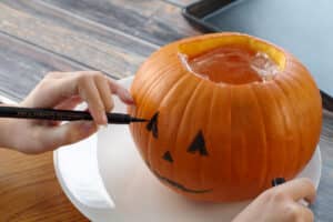 face being drawn on pumpkin with edible marker