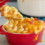 Mac and Cheese with tomatoes being lifted out of red bowl with spoon