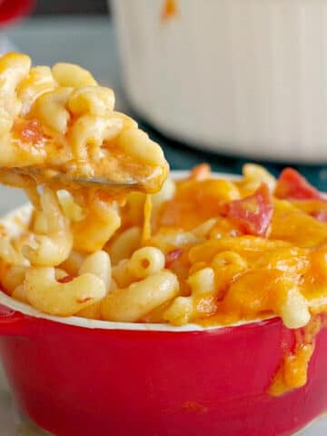 Mac and Cheese with tomatoes being lifted out of red bowl with spoon