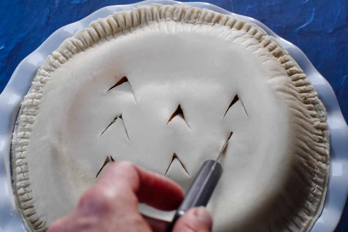 8 slits being made in pie shell (with a small paring knife)