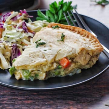 slice of turkey pot pie on a black plate with coleslaw