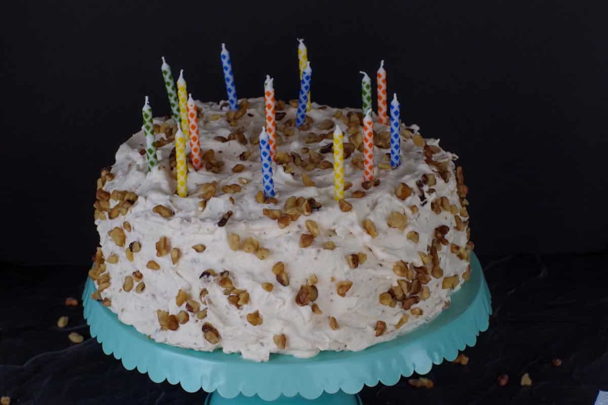 whole Ukrainian Walnut Torte with candles on top, on blue cake stand