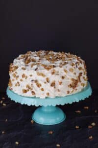 cake decorated with walnut pieces on a blue cake stand