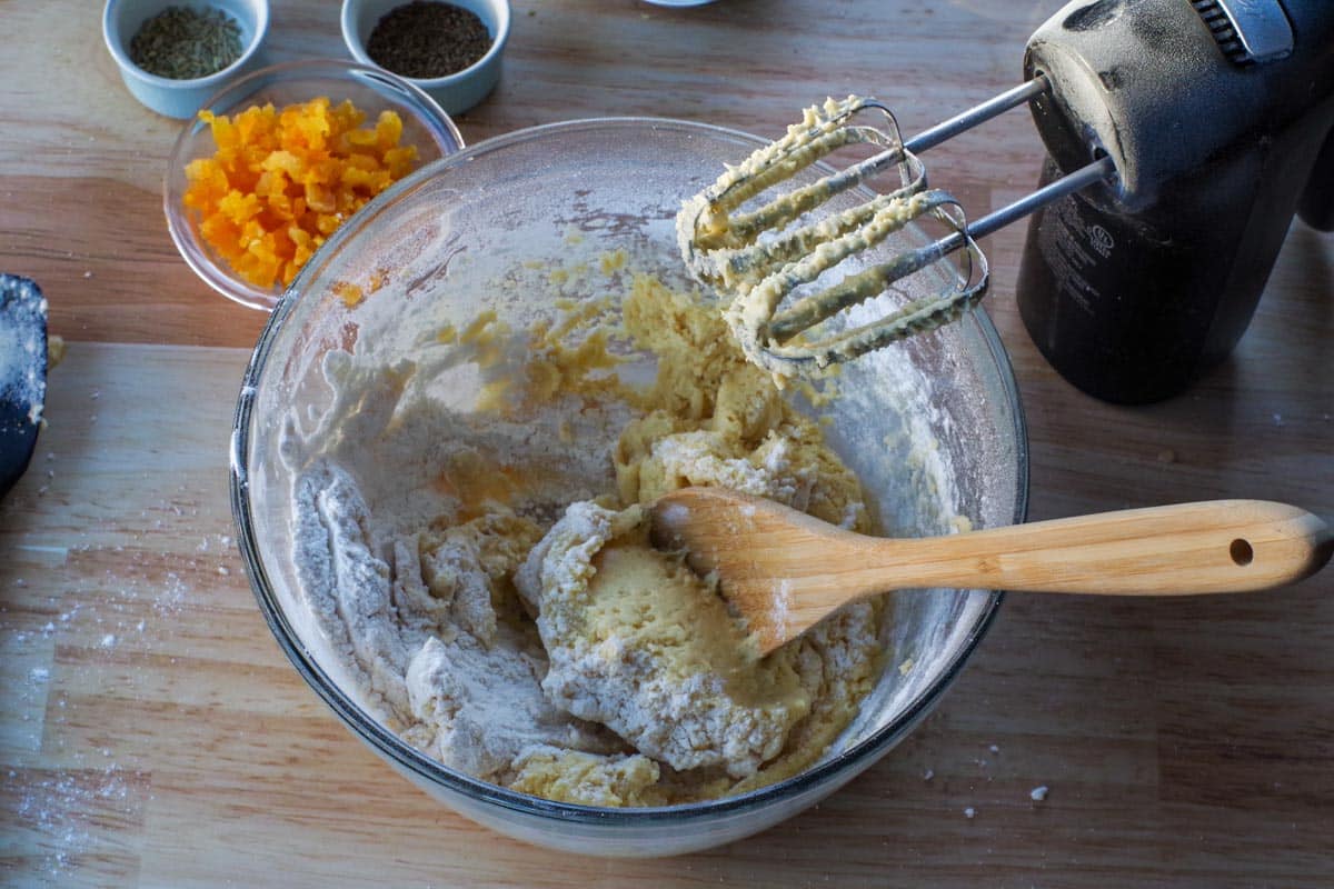 flour added to mixture, in bowl with wooden spoon