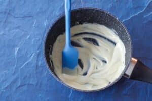 melted white chocolate in a pot with blue spatula