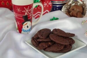 chocolate orange cookies on a white plate with a cup of coffee and a Terry's chocolate orange in the background