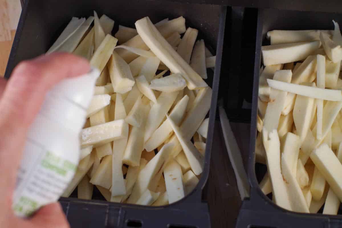 spraying oil on parsnip fries in air fryer drawer