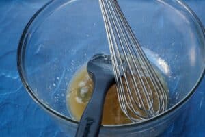 leftover pecan pie filling in large glass bowl with metal whisk and black silicone spatula