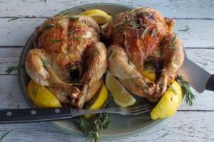 2 air fryer roast chickens on a green plate with lemon wed