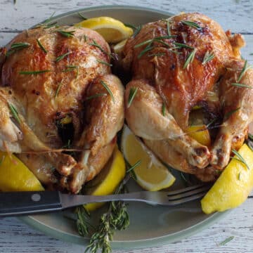 2 air fryer roast chickens on a green plate with lemon wedges